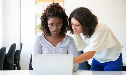 Front view of confident women talking while working with laptop. Thoughtful ladies discussing some work issues. Technology concept